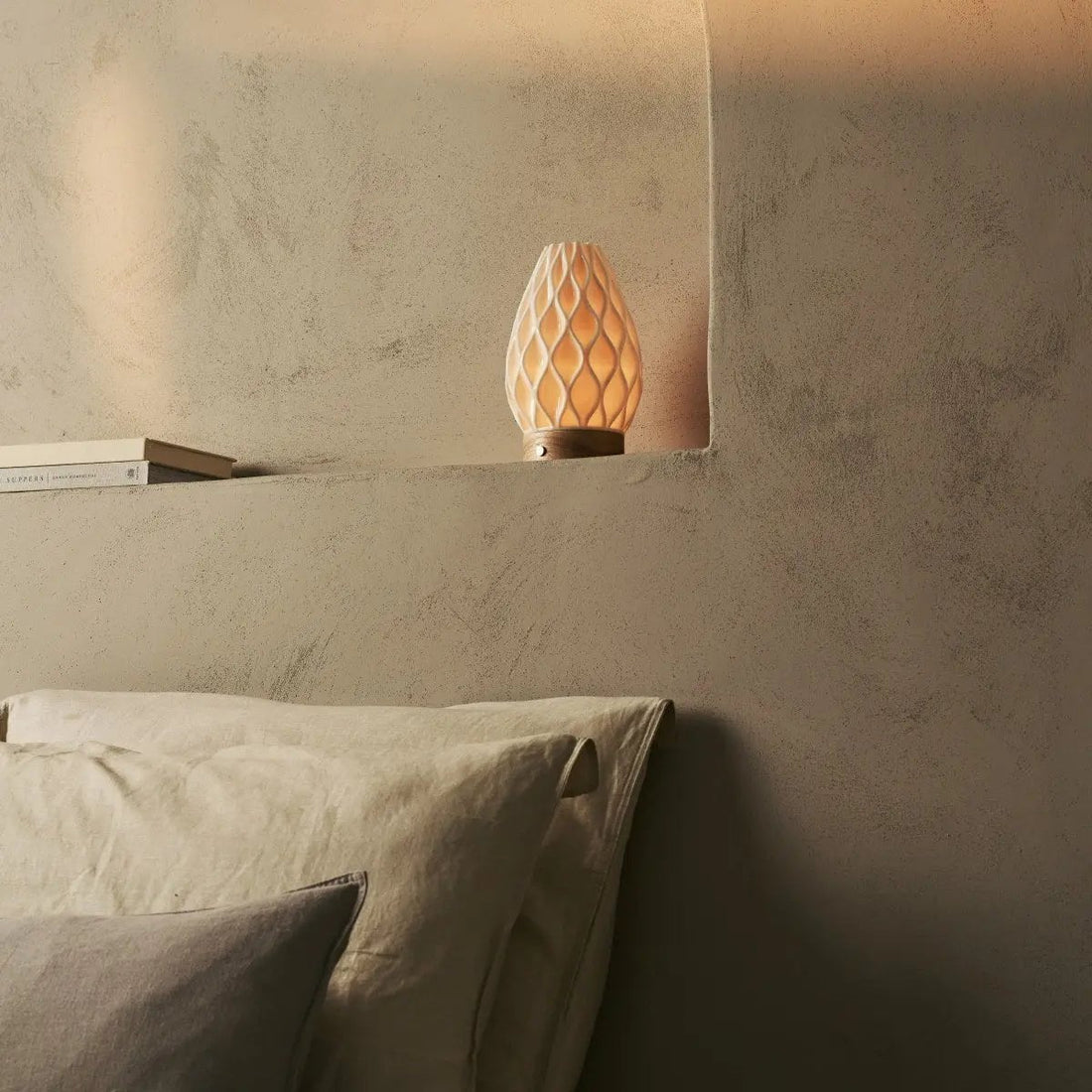 Compact cordless table lamp on a minimal bedside table in a calm bedroom interior