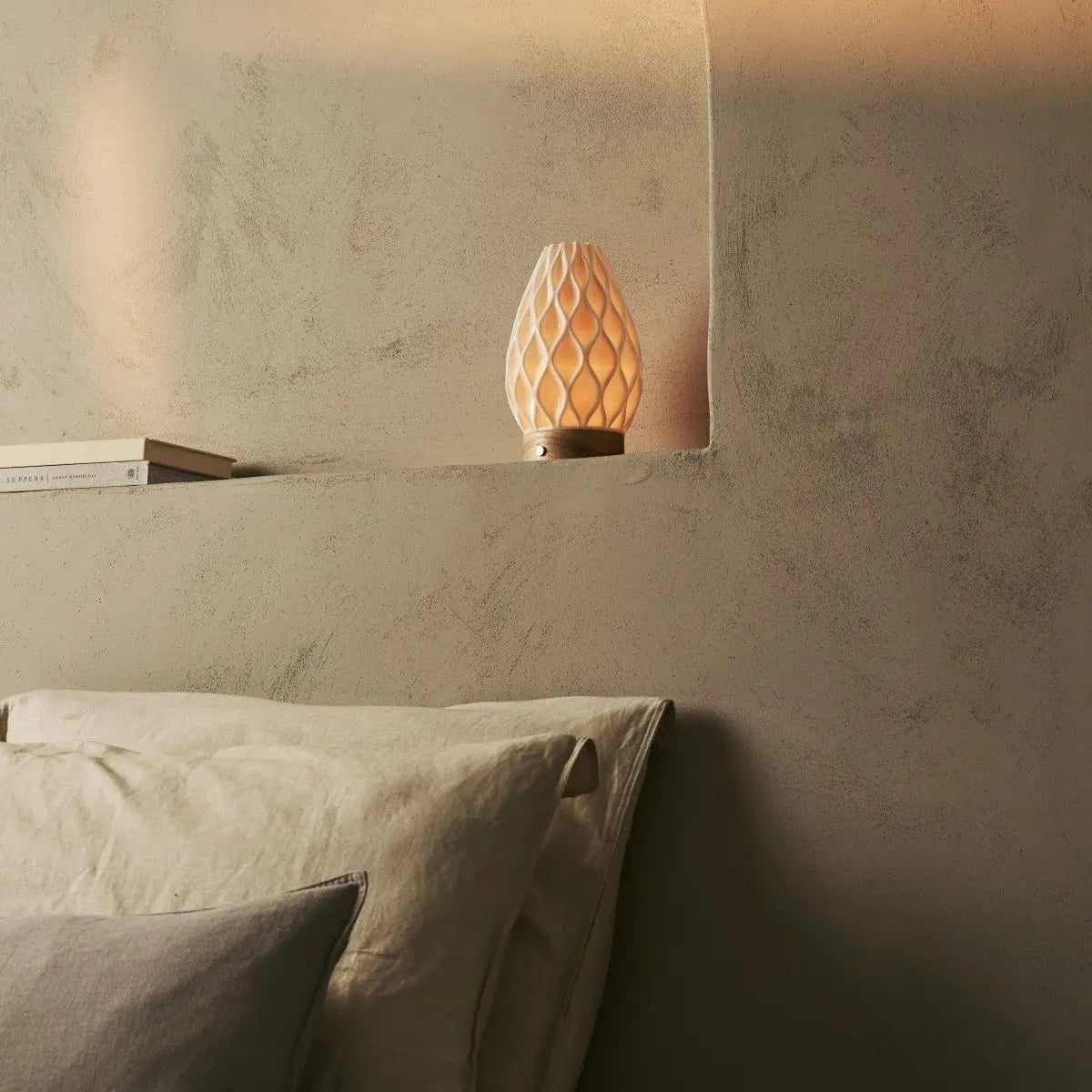 Compact cordless table lamp on a minimal bedside table in a calm bedroom interior