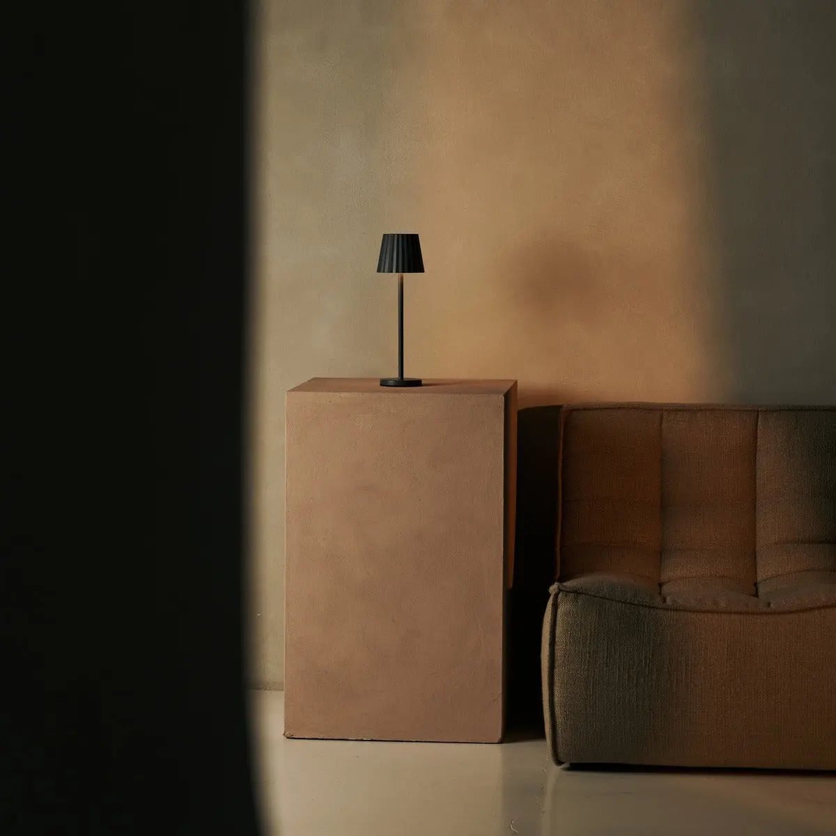 Cordless table lamp placed on a bedside table in a minimal interior