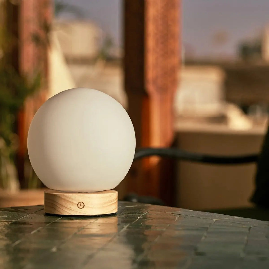 Rechargeable cordless table lamp on a small balcony table in spring evening light