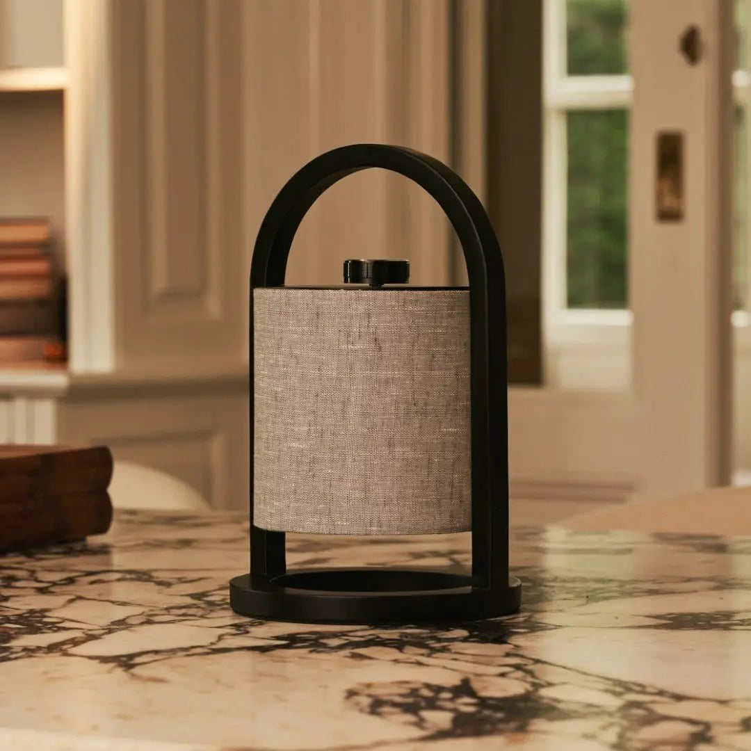 Table lamp with black arch and textured beige shade on a marble surface