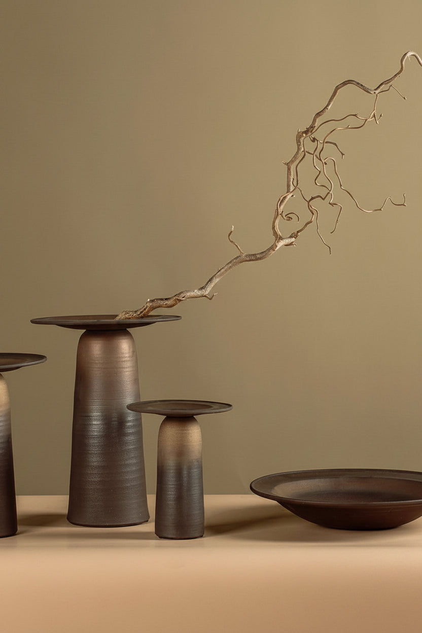 Decorative bronze bowls on a beige surface with a branch