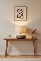 Table lamp with textured ceramic base and beige fabric shade on a white background