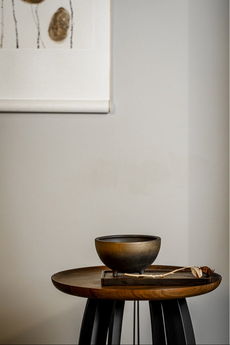Wooden stool with a black bowl on a neutral background