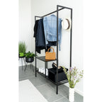 Black metal clothing rack with clothes, shoes, and a handbag in a room setting.