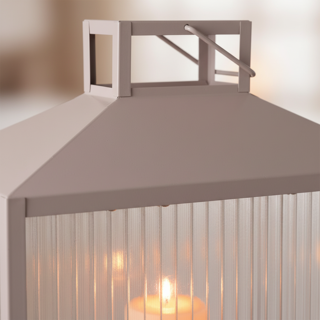 Close-up of Lucca lantern beige grey metal frame and glass panel with warm candlelight glow