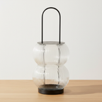 Lucena black metal ribbed glass lantern on oak surface with soft daylight and clean off-white background