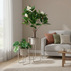 Set of two beige grey steel Marla plant stands with lush green plants in a warm Nordic living room corner