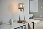 Stelo black tripod lamp with smoked glass globe on marble console with ceramic vase