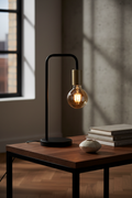 Modo black and gold arch table lamp on dark oak side table with ceramic object and books