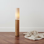 Totem Mud Floor Lamp staand op walnoot parket tegen witte muur