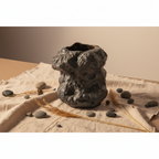 Black rock-look ceramic vase flat lay with pebbles, dried grass and linen cloth on neutral background
