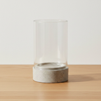 Grey ceramic and glass hurricane candle holder on oak surface with soft daylight and clean off-white background