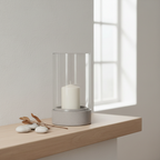 Grey ceramic glass hurricane candle holder on a mantelpiece in a Nordic interior with dried botanical styling