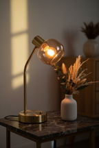 Libby brass and amber glass table lamp on dark marble side table with ceramic vase and botanicals