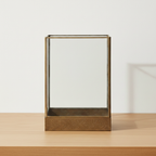 Manali antique brass metal and glass lantern on oak surface with soft daylight and clean off-white background