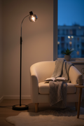 Fumoso gooseneck floor lamp over reading chair with warm amber glow