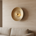 Volle Maan Brass Wall Lamp in woonkamer naast linnen bank