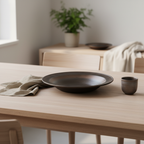 Ulfur East+West flat ceramic plate with bronze-to-black mineral glaze styled on a minimalist Scandinavian dining table