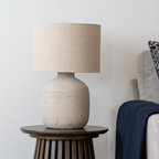 Close-up of Solea matte beige ceramic lamp base with linen drum shade and warm light
