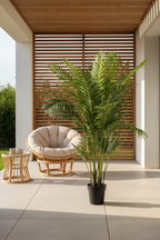 Large realistic artificial Areca palm on a sheltered terrace with warm afternoon light and rattan furniture