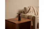 Bronze-to-black architectural ceramic vase on a walnut side table in a warm minimal living room
