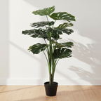 Tall realistic artificial Monstera plant on oak floor with soft daylight and clean off-white background