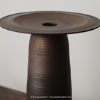 Close-up of tall ULFUR ceramic vase showing the two-piece construction and bronze to black mineral glaze texture