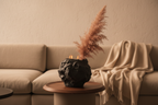 Black rock-texture ceramic vase on a walnut side table in a warm minimal living room