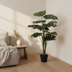 Tall realistic artificial Monstera plant with large split leaves styled in a Scandinavian living room corner