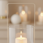 Close-up of beige glass and metal hurricane candle holder with warm candlelight glowing inside