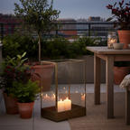 Manali antique brass lantern on a sheltered terrace at dusk with warm candlelight and potted plants
