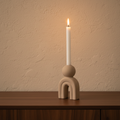 Bello stoneware candle holder close-up on walnut console, lit taper