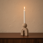 Bello stoneware candle holder close-up on walnut console, lit taper