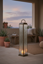 Herslev tall antique brass lantern on a sheltered terrace at dusk with warm candlelight glow