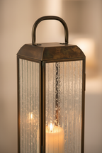 Close-up of Herslev lantern brass frame and glass panel with warm candlelight glow
