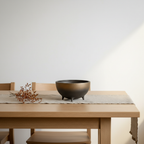 Otaru East+West hemispherical ceramic bowl with bronze-to-black mineral glaze styled on a Scandinavian dining table