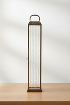 Herslev tall antique brass glass lantern on oak surface with soft daylight and clean off-white background