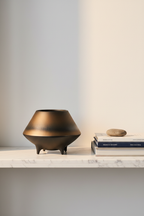 Otaru S bronze-to-black ceramic bowl styled on a marble shelf with art books and a smooth stone