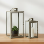 Set of two Corfu green steel and glass lanterns on oak surface with soft daylight and clean off-white background