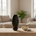 Matte black RUDAL microcement vase grouped with ceramic bowl and pebble on a Nordic sideboard