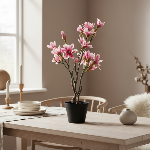 Tall slender realistic artificial magnolia tree on a dining table in a warm Nordic interior with soft natural light