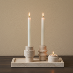Luma travertine tealight holder set close-up, oak surface, limewash wall, lit candles
