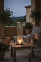 Herslev tall antique brass lantern on a sheltered terrace at dusk with warm candlelight glow