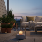 Grey ceramic glass hurricane candle holder on a sheltered terrace at dusk with warm candlelight