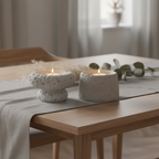 Set of two grey cement candle holders styled on a Scandinavian dining table with warm candlelight and linen