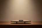 Bronze-to-black ceramic plate displayed flat on a walnut console with a smooth stone inside